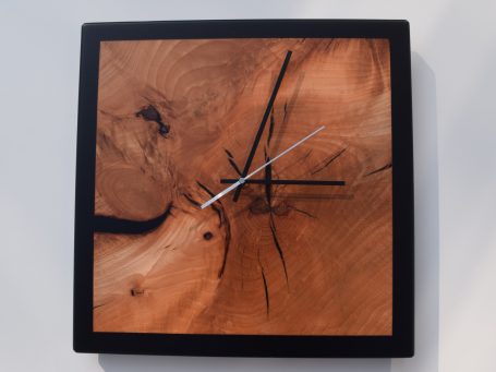 Eine Wanduhr aus holz mit einer schwarzen Epoxidharzumrandung.