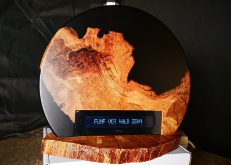 Eine runde Tischuhr mit Zeitanzeige in Worten mit Apfelholz und schwarzen Epoxidharz.