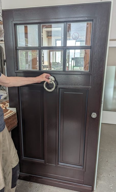 Dunkelbraune Haustür mit Glaseinsatz sowie runden Metallbeschlägen auch einem Anklopfer