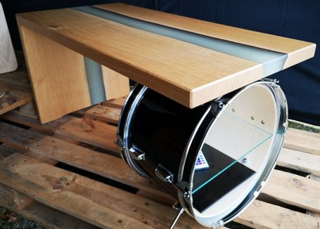 Ein Couchtisch mit Basstrommel als Standfuss und blau fluoreszierender Epoxidharzeinlage. 