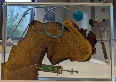 Deko Arztpraxis aus Holz und Epoxidharz. Eingegossen wurden ein Stetoskop, Spritze und Hämmerchen.