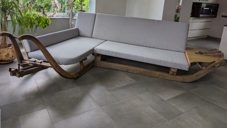 Aus zwei uralten Transportschlitten ist eine Eckcouch entstanden. Die graue Polsterung passt zum braunen Schlitten.